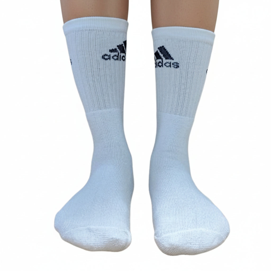 A pair of white Adidas crew socks worn on a person's legs, shown against a plain white background.